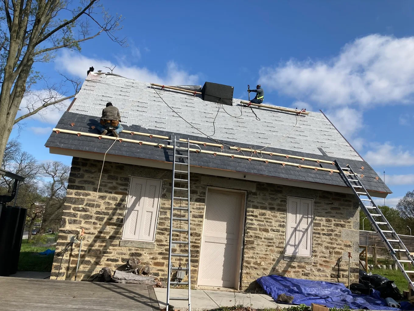 Workers installing a new slate roof on a stone house in Baltimore